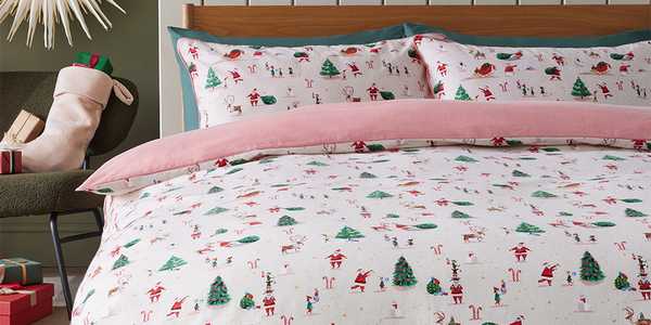 Pink and white Christmas themed bedding with Christmas trees, Santa, reindeers and elves print. 